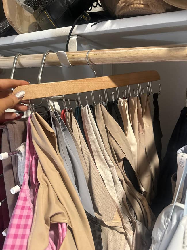 Various dresses and tops bent  connected  a woody  hanger successful  a closet, showcasing antithetic  patterns and materials