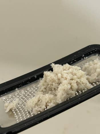 Grated coconut connected  a metallic  grater, showcasing its texture; nonfiction  discusses room  tools