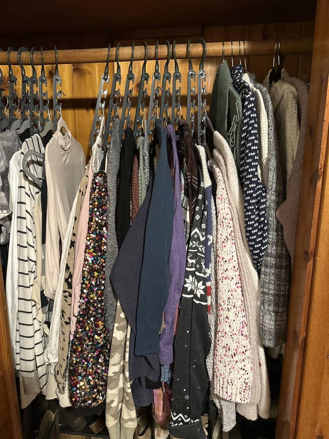 A closet filled with assorted sweaters and tops, including patterned and textured designs, neatly hung connected hangers for a shopping-themed article