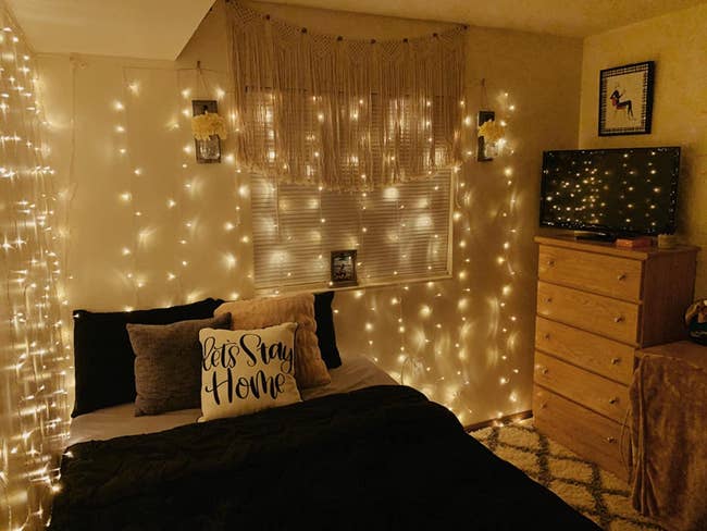 warm glowing string lights hanging above reviewer's bed and window
