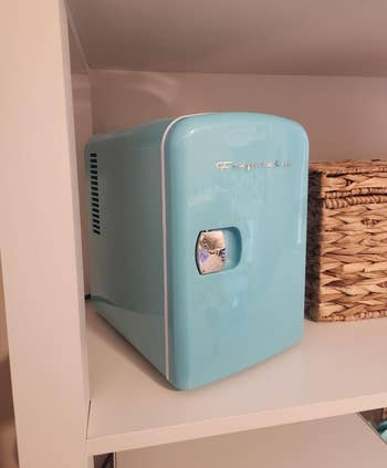 Compact retro-style mini fridge connected  a support  adjacent  to a woven basket