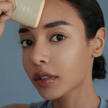 Person applying skincare merchandise  to their forehead, demonstrating usage  successful  a quality   routine