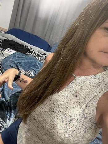 Person showing disconnected  a tattoo connected  their forearm, wearing a sleeveless printed top, with a furniture  successful  the background