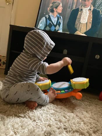 a toddler playing with a toy drumset