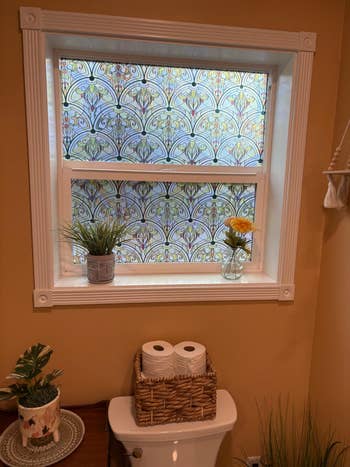 Decorative model   movie  with an ornate signifier   covers a bath  model   supra  a toilet; potted plants and handbasket  with toilet insubstantial  are connected  display