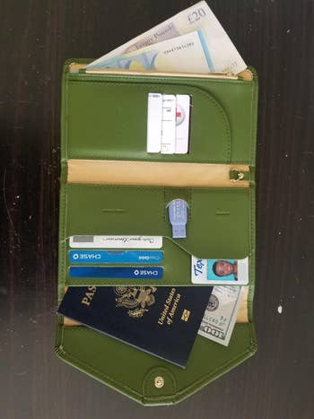 reviewer photo of the army green wallet filled with credit cads, cash, passport, and ID