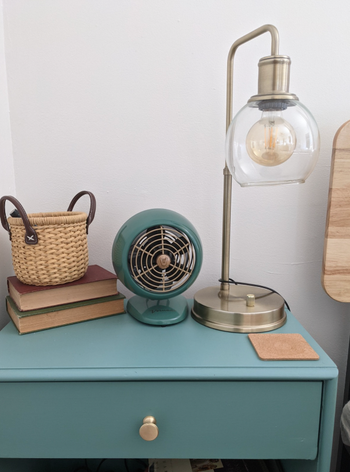 reviewer's brass and blue fan on a bedside table