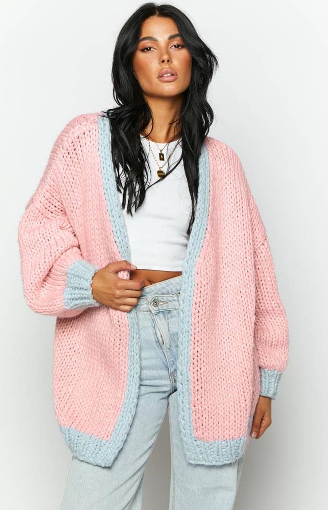 a model in a pink knit sweater with light blue trim