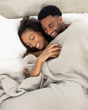 Two people snuggling under the blanket in grey
