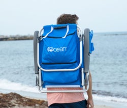 person carrying the blue chair as a backpack on a beach