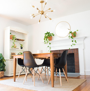 Interior dining area with a wooden table, two chairs, a fireplace, plants, and shelves for shopping-focused content