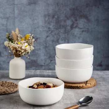 Four white stackable bowls with uneven edges