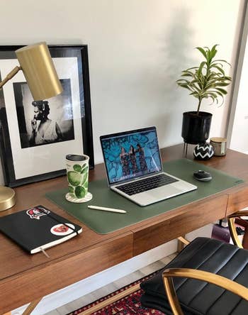 Reviewer pic of the rectangle desk mat in green with laptop, coffee, mouse and pen on it 