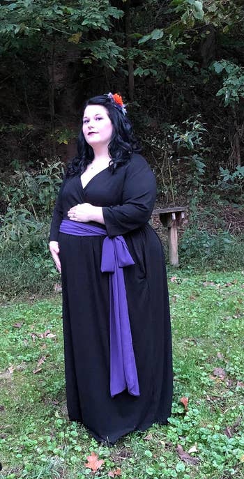 reviewer posing, holding belly wearing black wrap maxi dress 