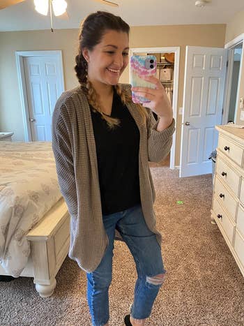 A reviewer taking a mirror selfie while wearing the cardigan in gray