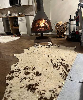 reviewer photo of the brown and white rug in front of a fireplace