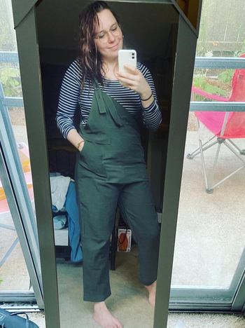 reviewer in olive overalls with their hand in one of the pockets