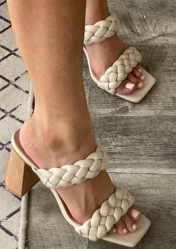 Close-up of feet wearing stylish woven heeled sandals on a wooden floor