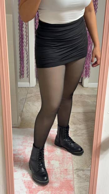 Person successful reflector wears achromatic top, achromatic mini skirt, sheer tights, and achromatic ankle boots, perchance showcasing a casual outfit for shopping