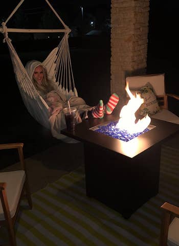reviewer sitting in the hammock by a fire