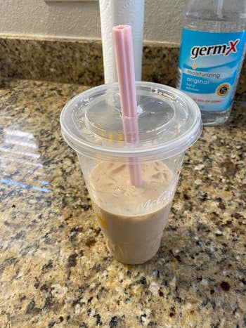 another reviewer's pink straw inserted in a to-go iced coffee cup