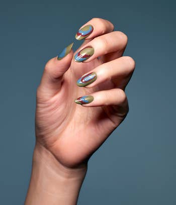 A manus  displays a manicure with intricate, creator  nail designs featuring abstract patterns, suitable for a fashion-forward buying  article