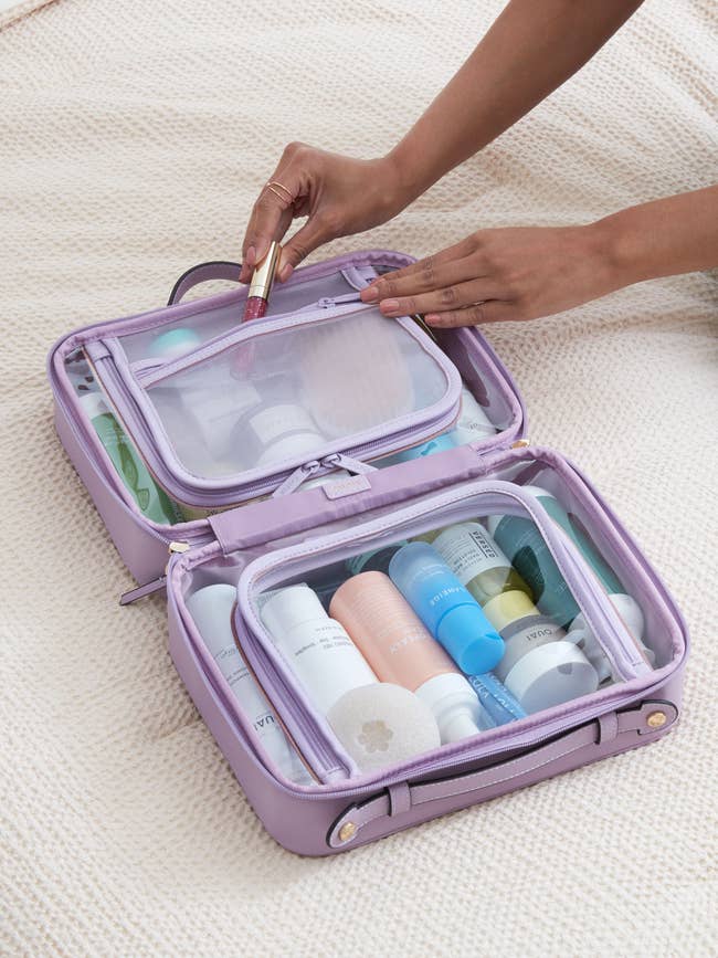model hand filling the open clear makeup bag with lilac edges