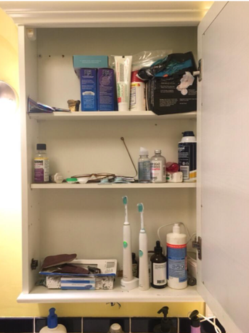  reviewer image showing their bathroom cabinet before using the organizer