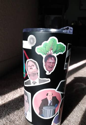 a tumbler covered in office stickers
