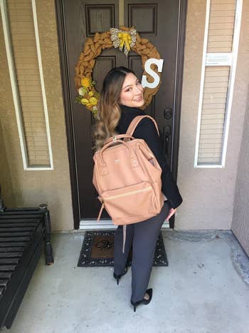Person smiling and wearing a stylish backpack, lasting successful beforehand of a welcoming doorway with decor. Suitable for a buying nonfiction connected backpack styles