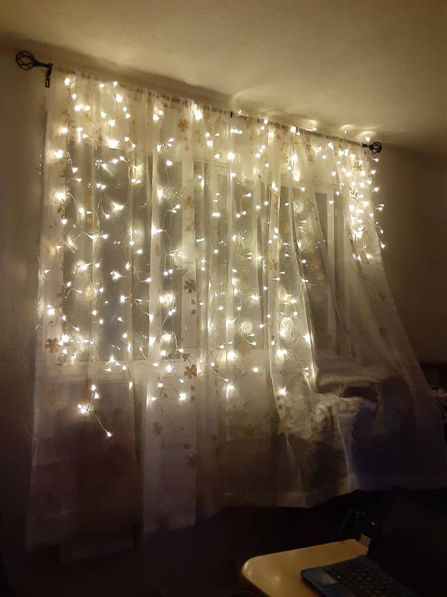 Sheer curtains with integrated string lights hung on a window, offering a cozy ambiance for home decor