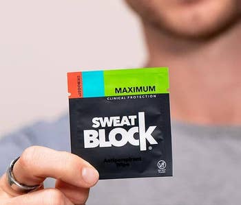 A person holds a pack of SweatBlock antiperspirant wipes, emphasizing
