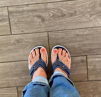 Person wearing sandals and blue jeans, photo focuses on feet