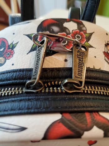 Close-up of a purse with a tattoo-style print and branded zipper pull
