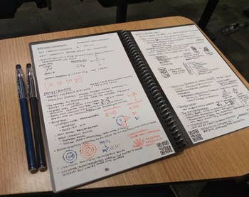 Reviewer's notes on pages in their reusable notebook, with pens next to the notebook