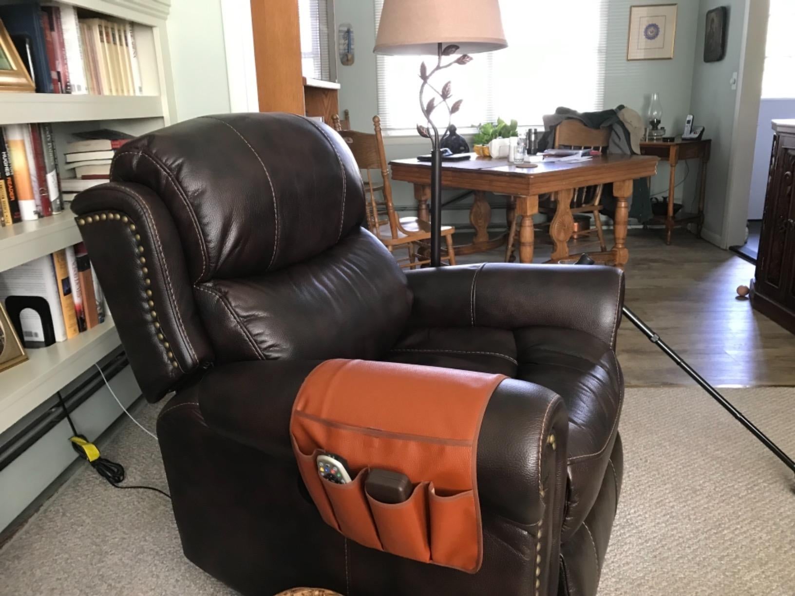 Reviewer's sofa caddy holding remotes over their sofa chair