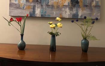 Reviewer image of products lined up with flowers inside on top of wooden table
