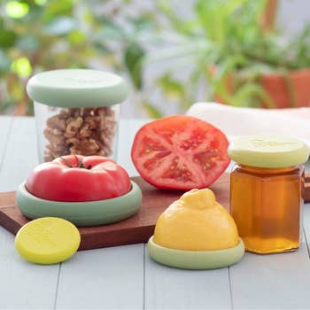 Various nutrient  savers connected  a table, sealing fractional  a tomato, a lemon, and covering walnuts and a chromatic  jar, showcasing their usage  for preserving freshness