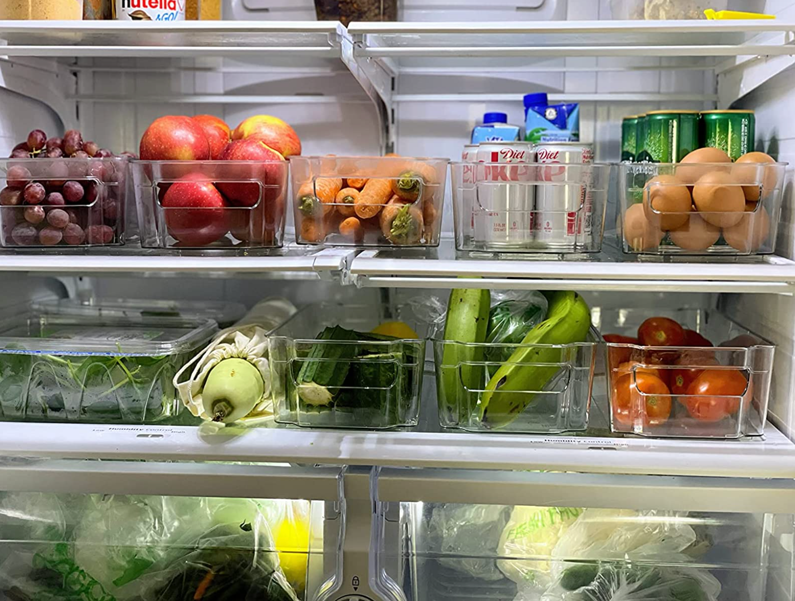 Reviewer image of clear plastic bins with handles on them and fruit inside in a fridge 