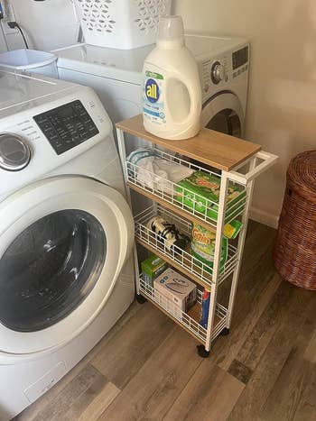 reviewer's white cart pulled out to show the laundry supplies it holds