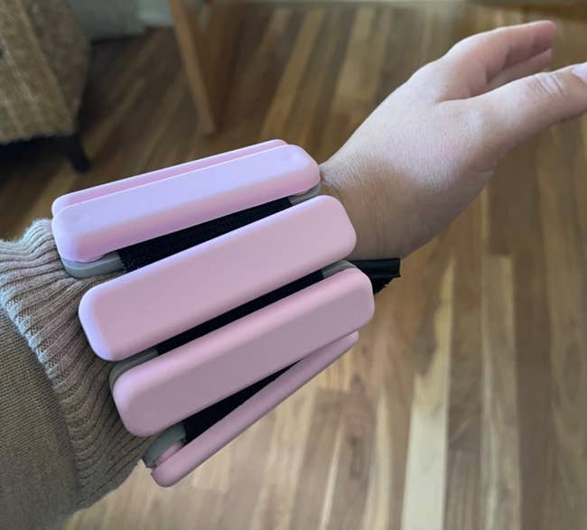 A reviewer photo of a wrist with a pink wrist weight worn indoors