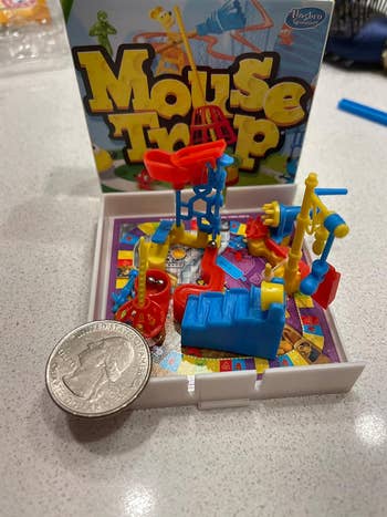 reviewer's miniature version of mouse trap set up next to a quarter for scale