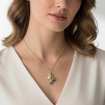 person wearing a golden necklace with tiny pendants, paired with a elemental v-neck top