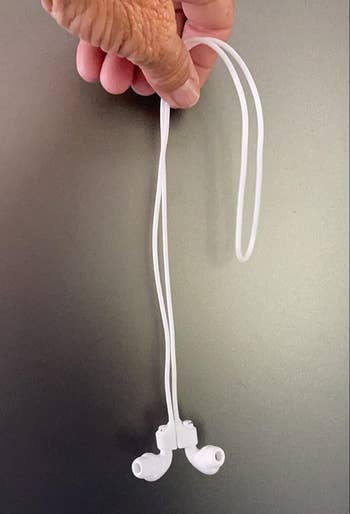 a white cord with two airpods attached to either end of it, magnetized to stick together 
