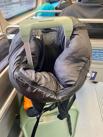 The tube full of clothes to become a travel neck pillow propped on a suitcase 