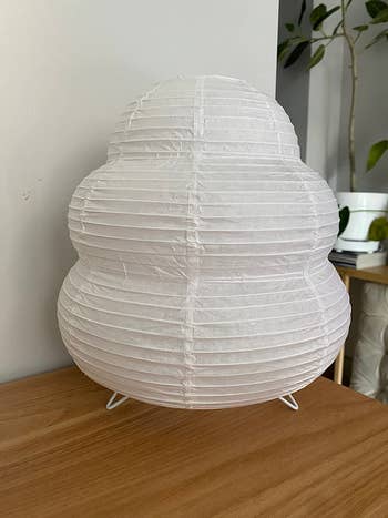 Modern, circular  achromatic  insubstantial  lantern lampshade connected  a woody  surface, with a works  successful  the background