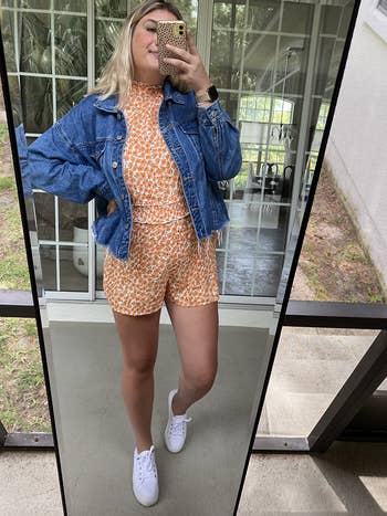 a reviewer wearing the romper in an orange print