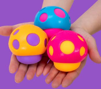 Hands holding 3  artifact  mushroom figures with polka dots, showcasing antithetic  textures for sensory play