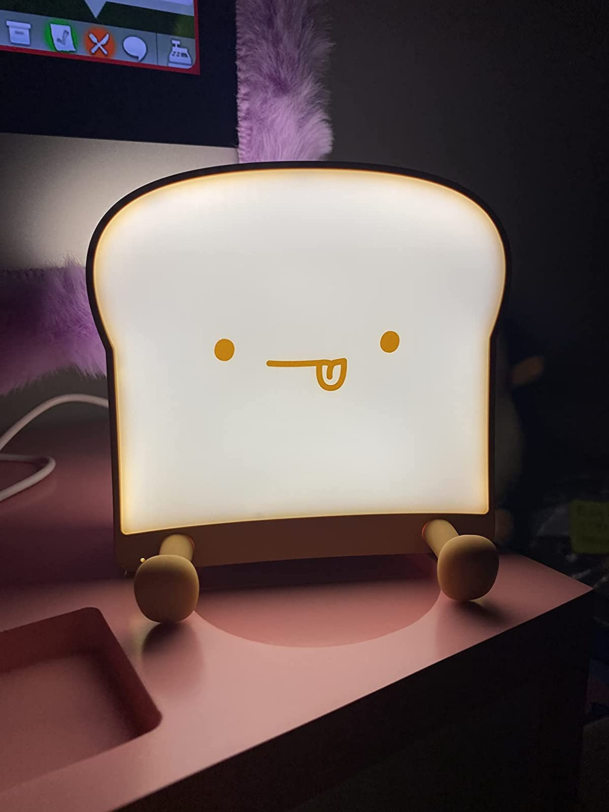 reviewer's illuminated toast night light with its tongue sticking out in a unfortunate mattress room