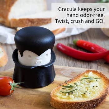 Vampire-themed garlic crusher on a table with fresh bread and ingredients; text highlights odor-free use